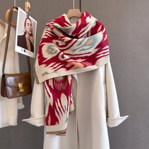 Detail of red geometric cashmere-like scarf with fringe on a white coat