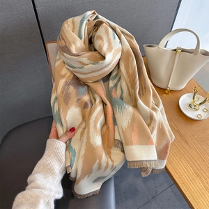 Detail view of ethnic geometric pattern and tassel trim on thick beige cashmere-like scarf