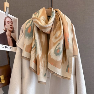 Close-up of thick beige jacquard scarf with geometric patterns and fringe detail