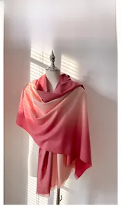 Detail of pink gradient cashmere-like scarf with fringe on a mannequin under soft sunlight