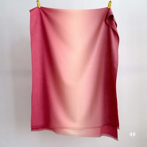 Detail of soft gradient cashmere scarf showing fuchsia to cream transition with tassels