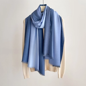 Detail of blue gradient cashmere-style scarf with soft texture and delicate fringe
