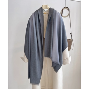 Detailed view of grey gradient cashmere shawl with soft fringe on wool coat