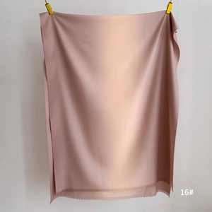 Detailed view of soft gradient pashmina shawl with tassel trim in beige and dusty rose pink