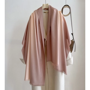 Detail of gradient cashmere-like shawl with fine tassels on a stylish long white coat