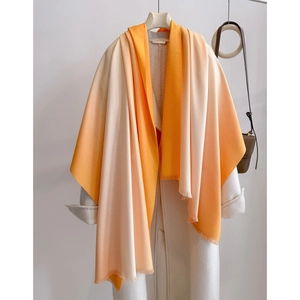 Elegant orange to beige gradient faux cashmere scarf with fringes over white coat