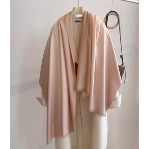 Detail of light pink cashmere-feel scarf with soft tassels on white wool coat