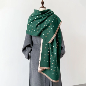 Macro detail of dark green thick scarf with pink heart patterns and soft fringe trim