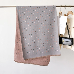 Detail view of heart pattern knit scarf with soft tassels and reversible dual-tone finish