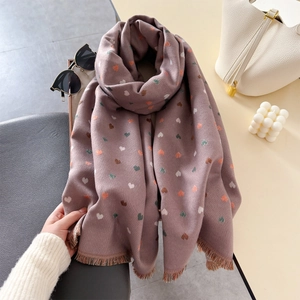 Close-up of pink heart-patterned winter scarf with fine tassels and soft texture