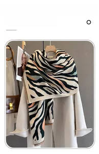 Detail of zebra print cashmere scarf with orange accents over a stylish white coat