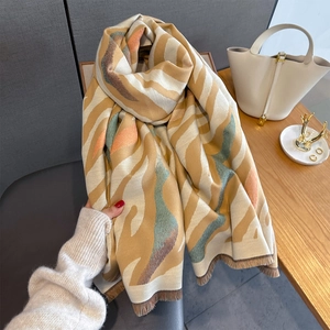Detailed texture of a soft beige scarf with mustard and teal abstract stripes and fringe
