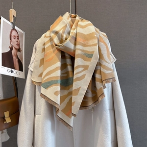 Detail of soft irregular wave pattern and fringe on beige cashmere-like autumn scarf