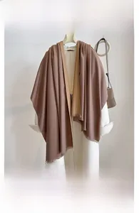 Detail of a thick double-sided pashmina shawl with fringe over a white coat
