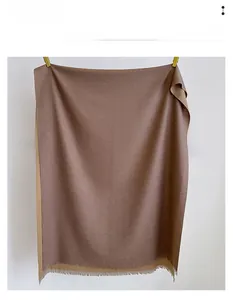 Detailed close-up of brown cashmere-like scarf with fringe edges and dual-tone design