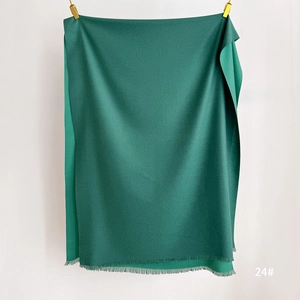 Close-up of dark green solid scarf showing soft texture and fine fringe edge detail
