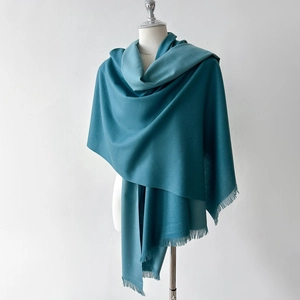 Detail shot of elegant dark teal cashmere shawl featuring exquisite fringe tassels