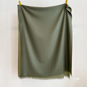 Detail of dark green cashmere-feel scarf showing soft fabric texture and fine fringe trim
