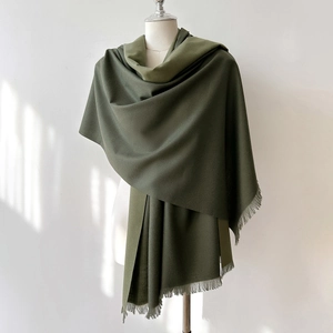 Detail view of olive green cashmere-like scarf showing soft texture and tassel edges