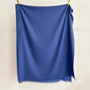 Detail of dark blue cashmere-feel scarf with soft fringe trim and thick texture