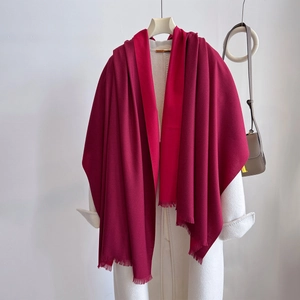 Detail of red cashmere-feel scarf with tassels draped over a white wool coat
