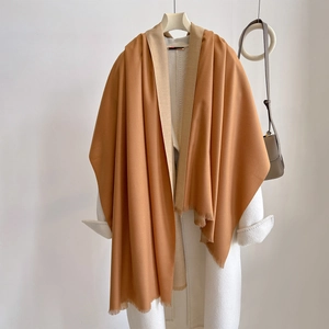 Close-up of caramel cashmere-feel scarf texture and fringe detail on white wool coat
