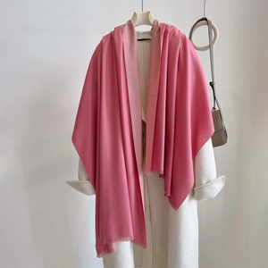 Close-up of pink cashmere-like scarf texture and fine tassels on white coat