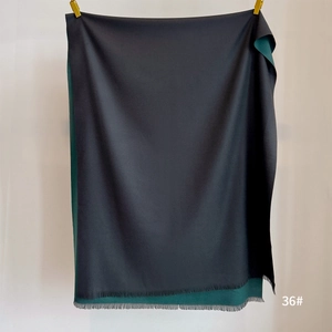 Close-up of high-quality cashmere scarf with fine tassels in black and dark green