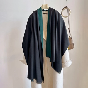 Detail of minimalist black and dark green cashmere shawl with fringe on wool coat
