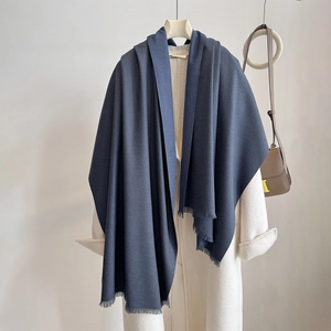Detail of navy blue cashmere-feel shawl with fringed edges over a white coat
