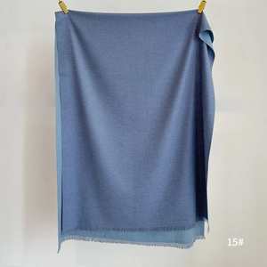 Detail of blue cashmere feel scarf with fine tassel edges and soft knitted texture