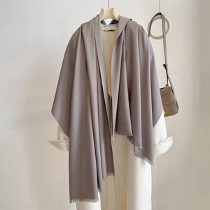 Macro detail of soft cashmere-feel fabric and fine fringe on a gray-purple shawl