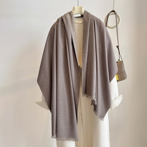 Detail of taupe cashmere scarf fringe texture draped on a white coat background
