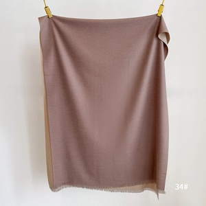 Detail view of double-sided cashmere-like scarf with tassels in mauve and camel tones