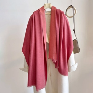 Solid rose pink cashmere-like scarf with fringe edges draped on a white coat