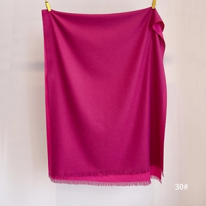 Detail view of rose red cashmere feel scarf with soft fringe edges and a smooth drape