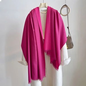 Close-up of bright pink cashmere-like scarf with fringe detail on a white coat