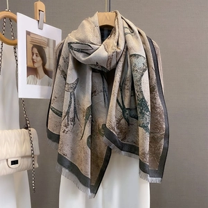 Vintage deer jacquard scarf in earth tones hanging on a wooden hanger with fringe details