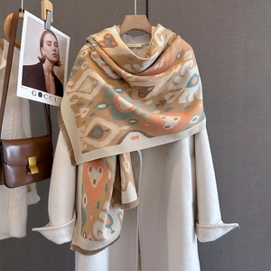 Detail of colorful geometric knit scarf with short fringe on elegant white wool coat