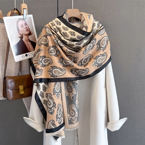 Detailed view of paisley print scarf with frayed edges draped over a white coat
