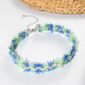Detail of woven lace choker with blue and green tassels, gold metallic threads and silver clasp