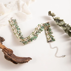 Close-up of woven lace choker necklace with vintage cream and green threads and silver clasp