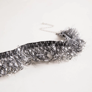 Macro detail of black and white woven lace choker with delicate feather-like fringe