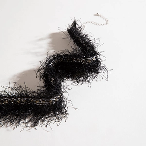 Detail of black fringe choker necklace with gold thread weaving and silver lobster clasp