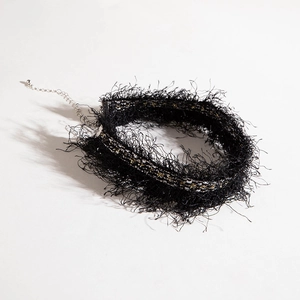 Macro view of bohemian black lace choker featuring fluffy fringe and adjustable chain