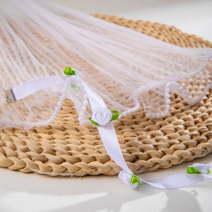 Detail of white bridal veil with pearl trim, handmade fabric rose and metal hair clip