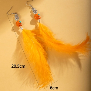 Détail de boucles d'oreilles en plumes orange avec crâne et mesure de 20,5 cm
