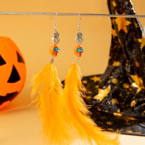 Boucles d'oreilles Halloween avec crâne, cœur et plumes oranges sur fond de citrouille