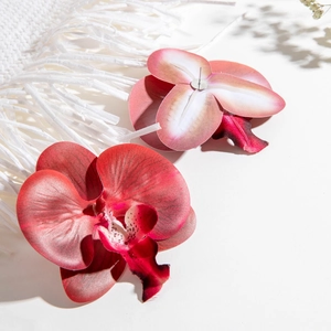 Close-up of realistic fabric orchid earrings in red and pink with petal textures
