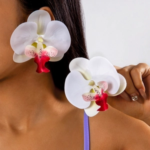 Macro side view of a model wearing large white orchid floral earrings with pink details